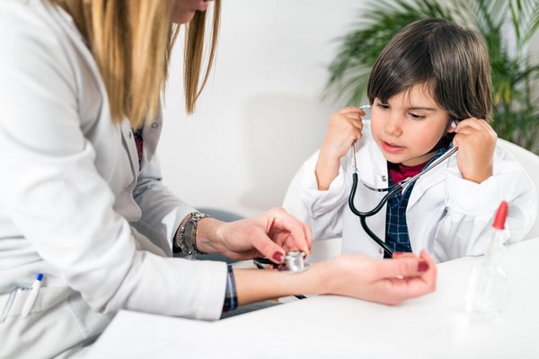 Ребенок на приеме у врача играет с фонендоскопом