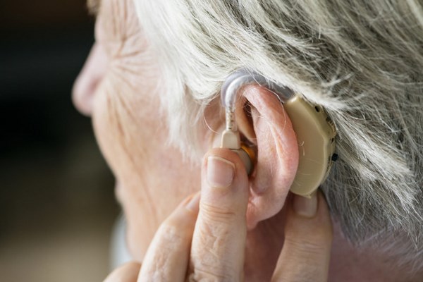 На фото – пожилая женщина со слуховым аппаратом