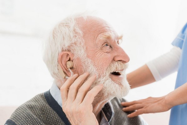 Довольный пожилой мужчина со слуховым аппаратом