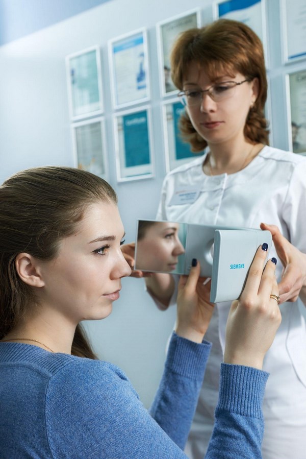 Наталья Хабловская показывает пациенту, как будет выглядеть слуховой аппарат на ухе