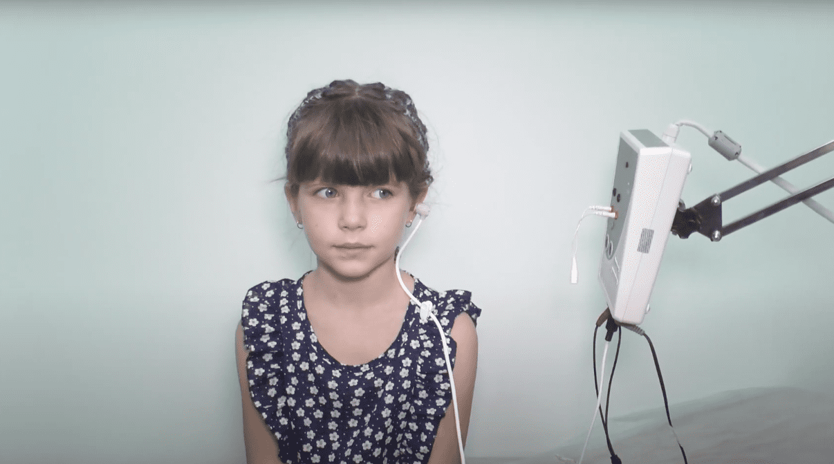 Девочка во время обследования слуха методом отоакустической эмиссии