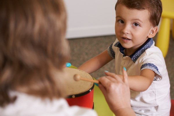 На фото – сурдопедагог учит ребенка реагировать на звук